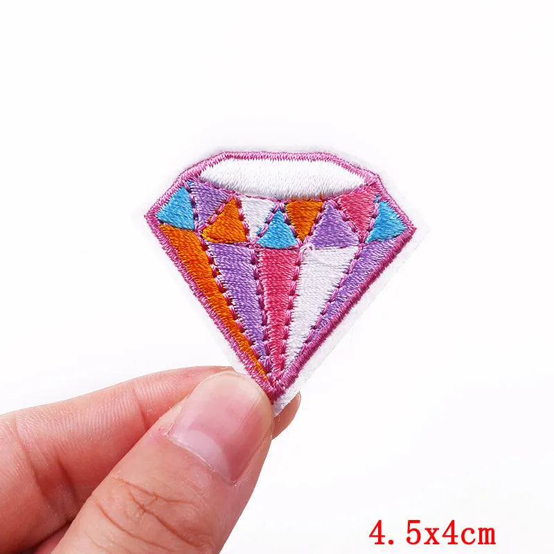Colorful diamond-shaped patch held by a hand with a white background