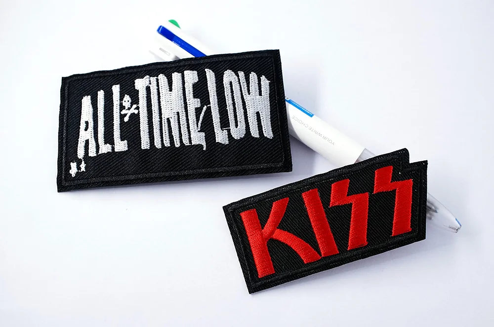 Two patches, one with 'All Time Low' and the other with 'KISS', on a white background.