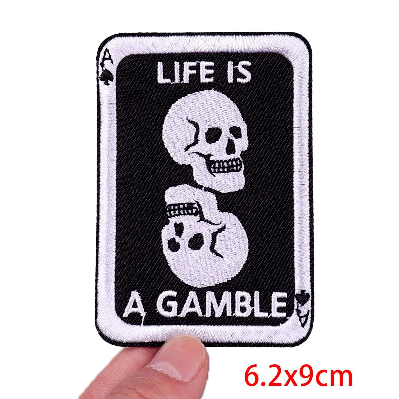 Patch with skull design and 'Life is a Gamble' text held by a hand, with dimensions displayed.