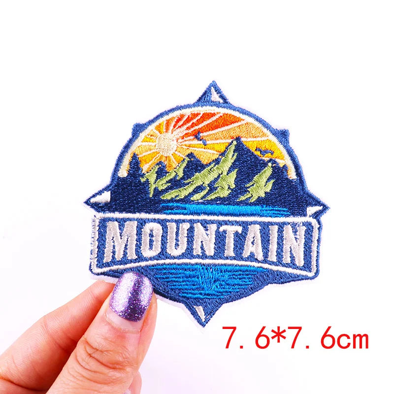 Embroidered patch with mountain design held by a hand, size 7.6*7.6cm.