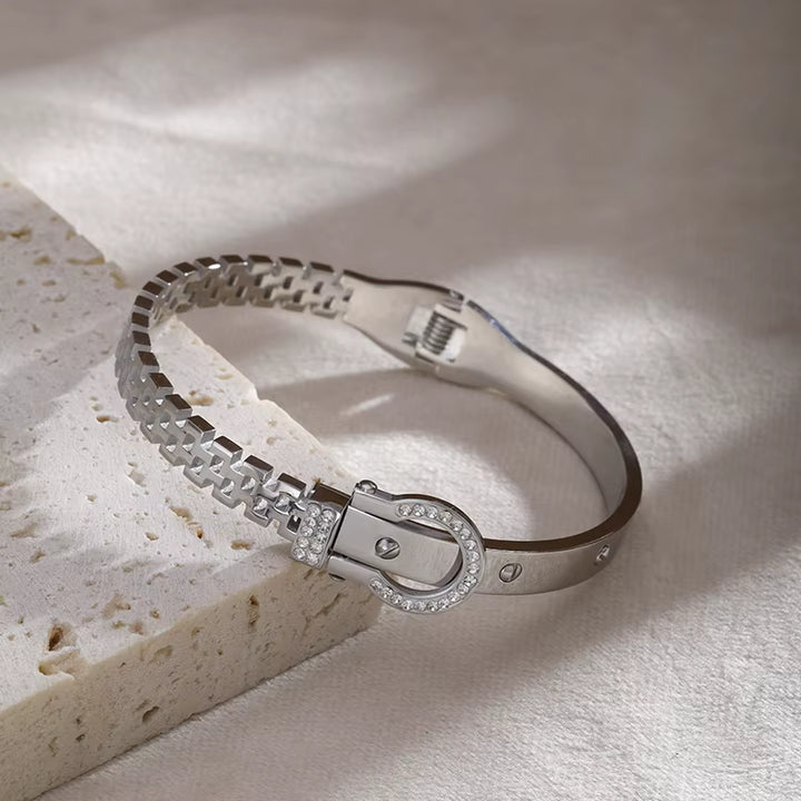Silver bracelet with a clasp on a textured surface