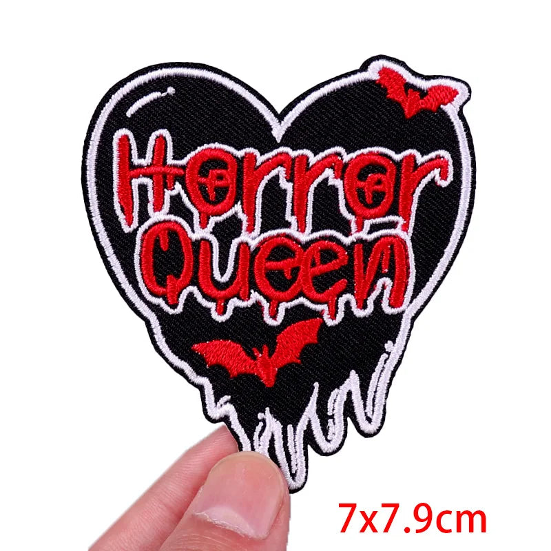 Heart-shaped patch with 'Horror Queen' text and red bats, held by a hand on a white background.
