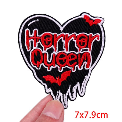 Heart-shaped patch with 'Horror Queen' text and red bats, held by a hand on a white background.