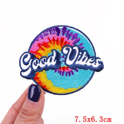 Colorful patch with 'Good Vibes' text held by a hand on a white background