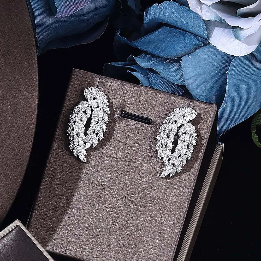Pair of silver earrings on a brown jewelry box with blue flowers in the background