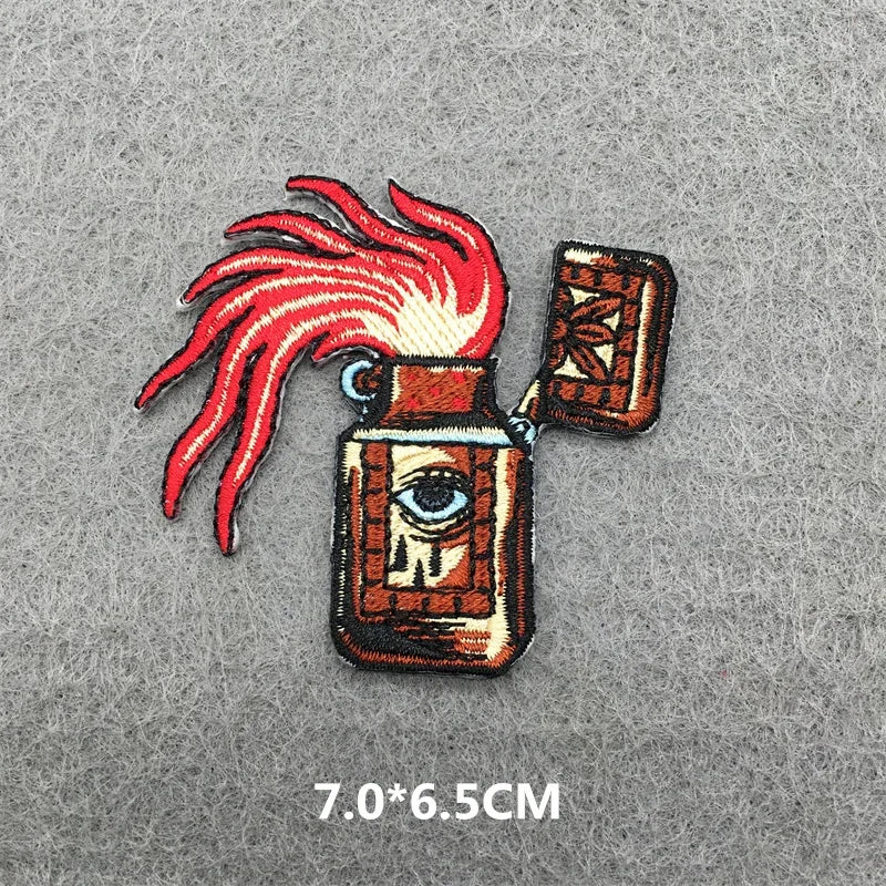 Embroidered patch with eye design and red feathers on a gray background