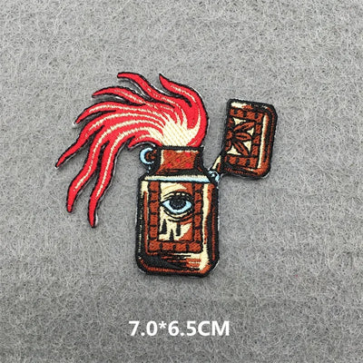 Embroidered patch with eye design and red feathers on a gray background