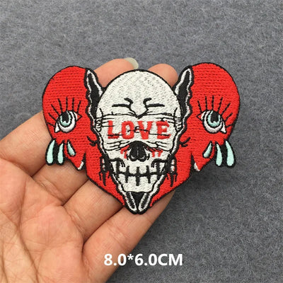 Skull patch with red hearts and 'LOVE' text held in a hand on a gray background