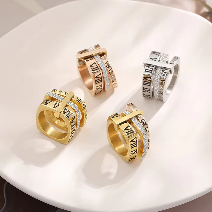 Gold and silver rings with Roman numeral designs on a white surface