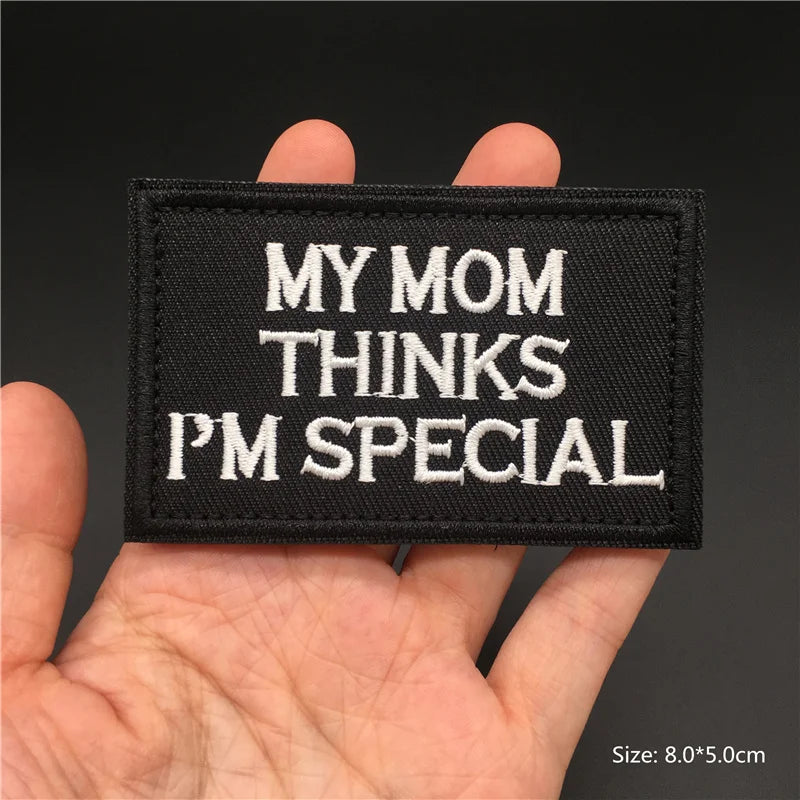 Black patch with 'My Mom Thinks I'm Special' text held in a hand against a dark background
