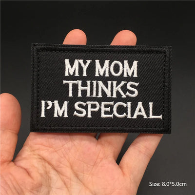 Black patch with 'My Mom Thinks I'm Special' text held in a hand against a dark background