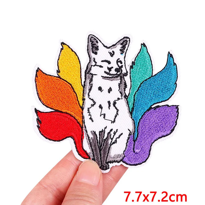 Sticker of a cat with rainbow feathers held by a hand, with dimensions 7.7x7.2cm.