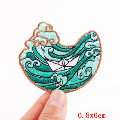 Embroidered patch with wave design held by a hand on a white background