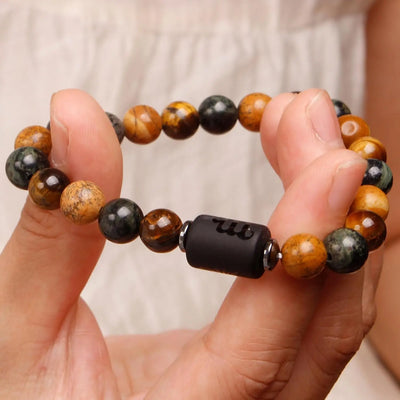 Hand holding a beaded bracelet with a focus on the black central bead.