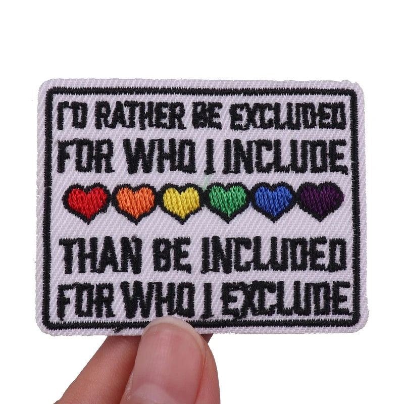 Embroidered patch with text and rainbow hearts held by a hand on a white background
