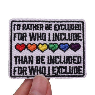 Embroidered patch with text and rainbow hearts held by a hand on a white background