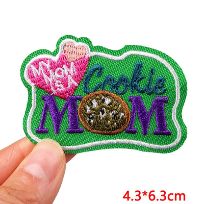 Embroidered patch with 'My Mom is a Cookie Mom' text held by a hand, on a white background.