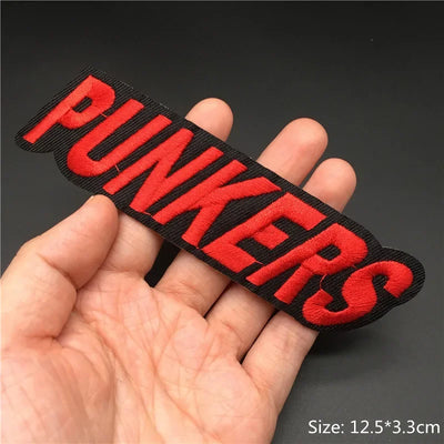 Red 'PUNKERS' patch held in a hand against a dark background