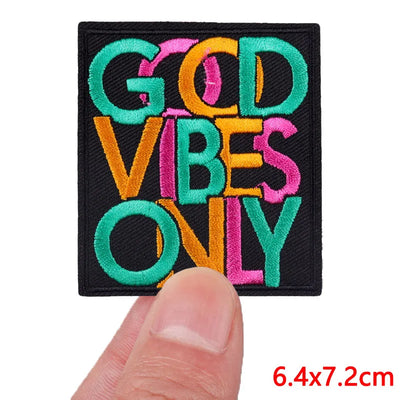 Embroidered patch with 'GOD VIBES ONLY' text held by a finger, on a white background.