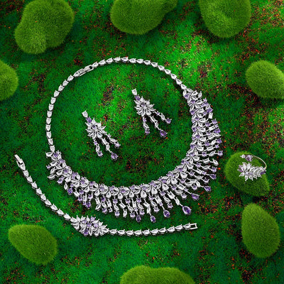 Silver jewelry set with purple stones on a green textured background