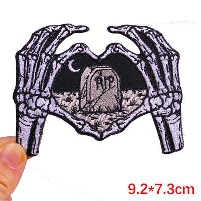 Embroidered patch with skeleton hands holding a tombstone design, held by a hand with measurement text '9.2*7.3cm'.
