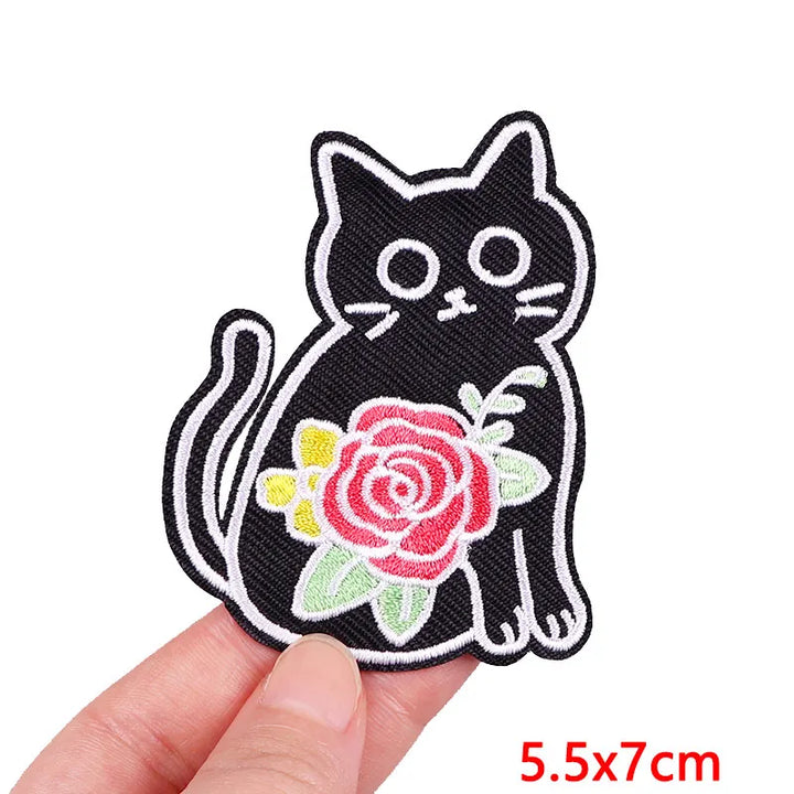 Black cat patch with a pink rose held by a hand on a white background