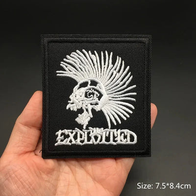 Black patch with white embroidered design and 'Exhilarated' text held in a hand against a dark background