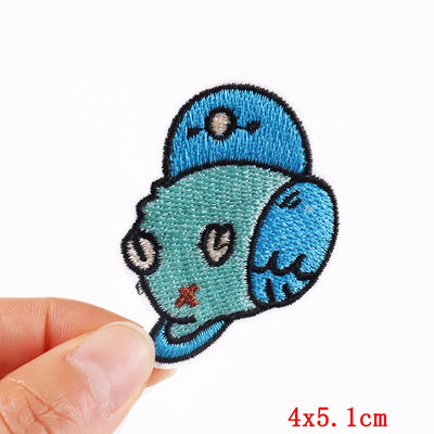 Blue cartoonish face patch held by a hand on a white background