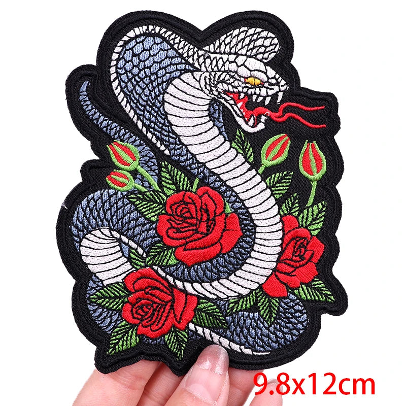 Embroidered patch with a snake and roses held by a hand, size 9.8x12cm.