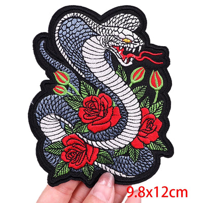 Embroidered patch with a snake and roses held by a hand, size 9.8x12cm.