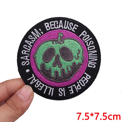 Circular patch with a skull design and text held by a hand on a white background