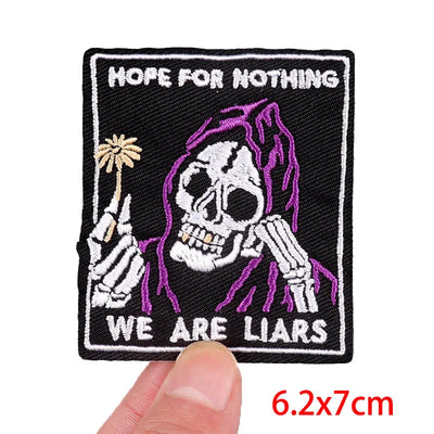 Patch with skeleton holding a palm tree and text 'Hope for Nothing, We Are Liars' held by a hand.