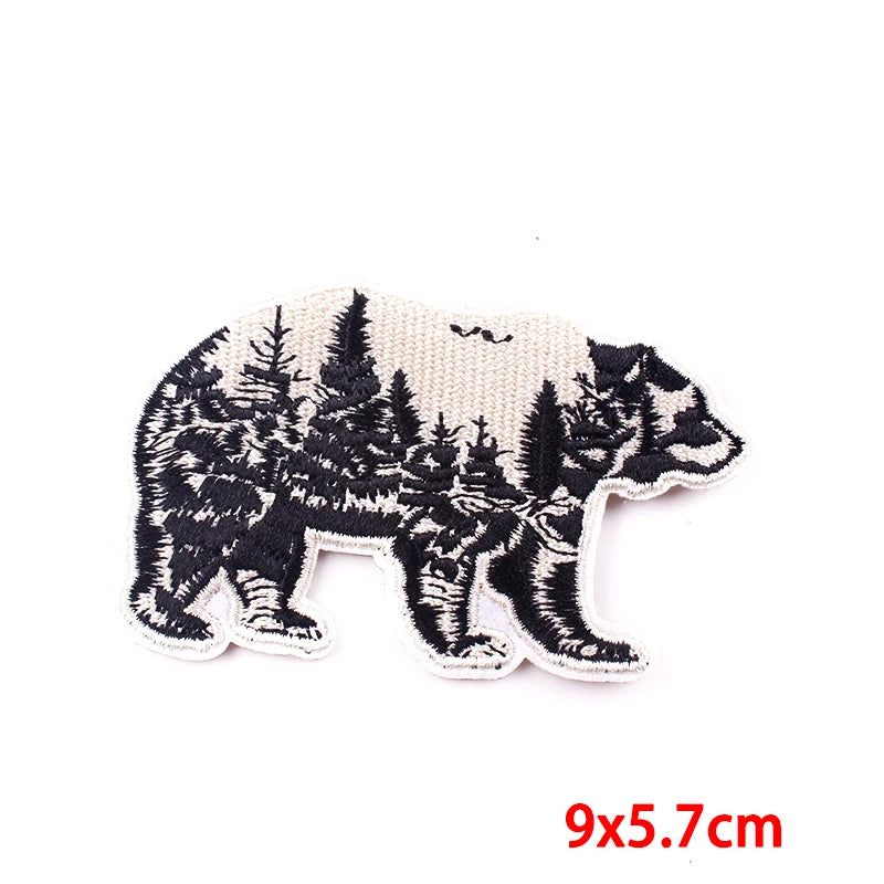 Embroidered bear patch with forest design on a white background