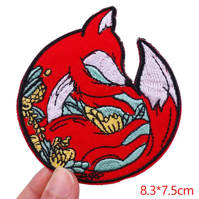 Embroidered patch of a red fox with goldfish on a white background