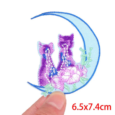Embroidered patch with two cats and a crescent moon on a white background