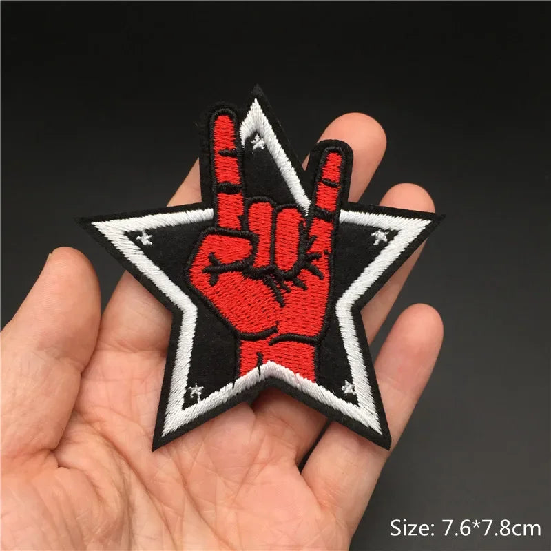 Hand holding a red rock hand embroidered iron-on star patch 7.6x7.8cm on a dark background