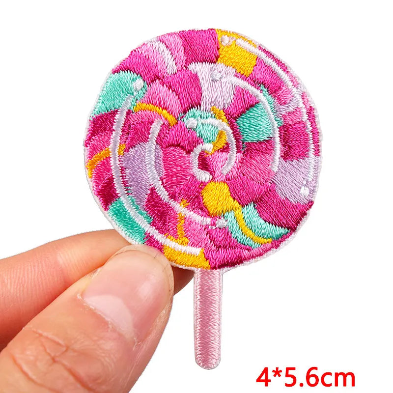 Colorful embroidered patch resembling a lollipop held by a hand on a white background
