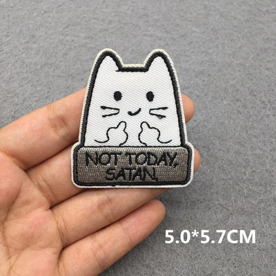 Cat-shaped patch with 'Not Today Satan' text held in a hand against a gray background