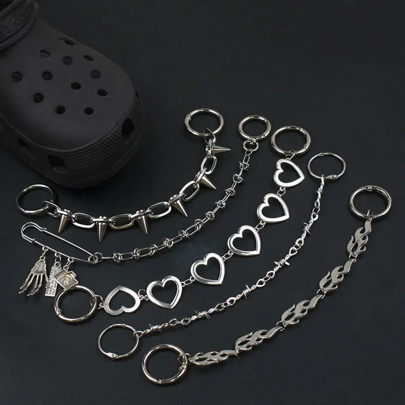 Silver chain for crocs with heart and spike designs on a dark surface.
