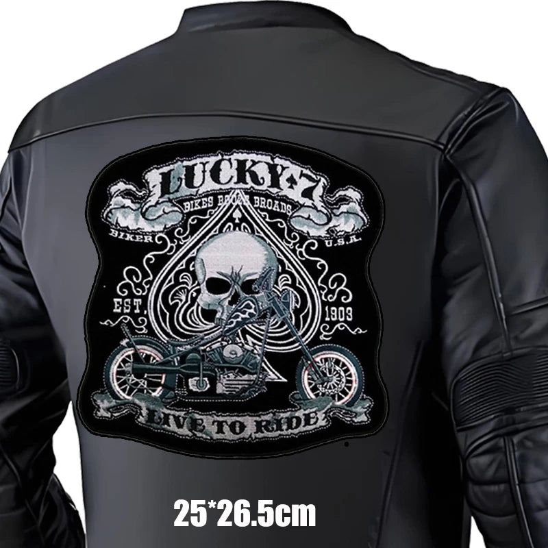 Black leather jacket with a large embroidered patch on the back featuring a skull and motorcycle design.