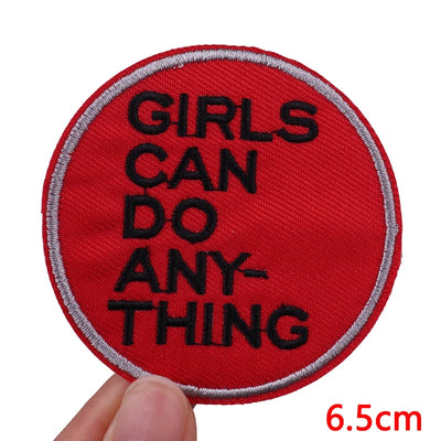 Red patch with 'GIRLS CAN DO ANYTHING' text held by a hand, with a measurement label at the bottom right corner.