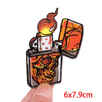 Embroidered patch of an open lighter with flame design held by a hand, on a white background.