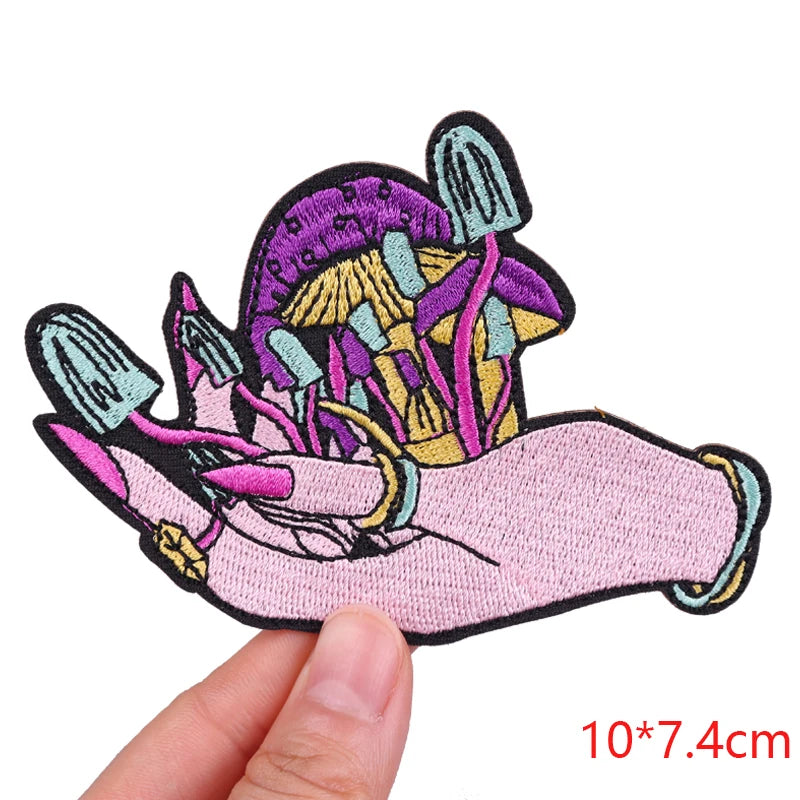 Embroidered patch of a hand holding mushrooms held by a hand, with dimensions 10*7.4cm.