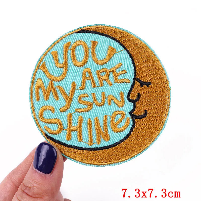 Embroidered patch with 'You are my sunshine' text held by a hand on a white background