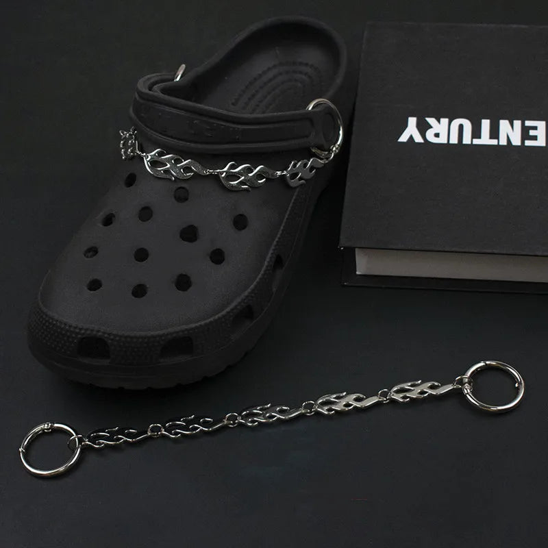 Black clog shoe with a silver chain on a dark surface, featuring the brand &