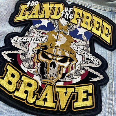 Patch with skull design, American flag, and text 'Land of the Free Because Brave' on denim fabric.
