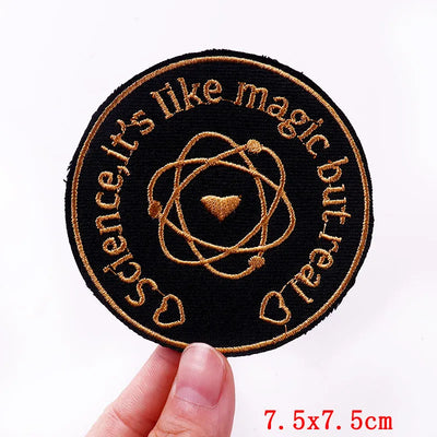 Circular patch with text and design held by a hand, on a white background