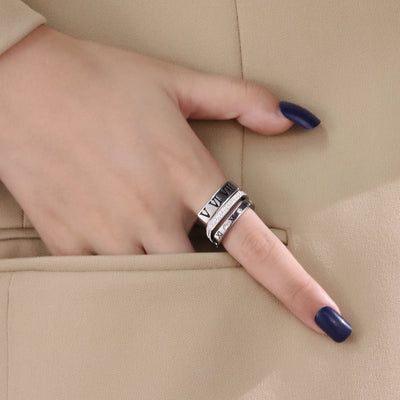 Hand wearing multiple silver rings on a beige background