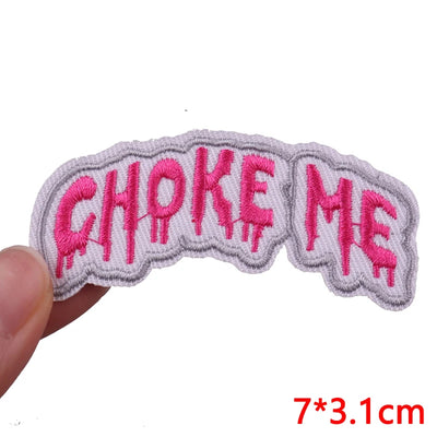 Embroidered patch with 'CHOKE ME' text in pink on a white background