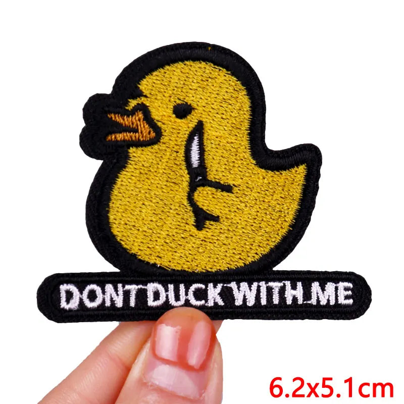 Yellow duck patch with 'Don't Duck With Me' text held by a hand on a white background
